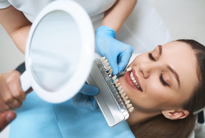 Joyful young female is visiting dentist for choosing veneers and improving her smile with specialist help